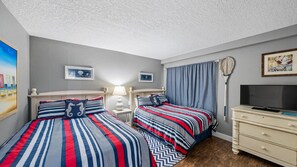 A bedroom with two beds, a television, and a tennis racket on the wall.