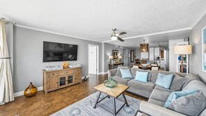 A modern living room with a grey sofa, wooden cabinet, and a television.