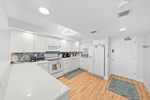 Una cocina moderna con armarios blancos, microondas, estufa y refrigerador.