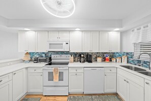 A modern kitchen with white cabinets, a microwave, stove, and dishwasher. - #803 Shores Club Oceanfront Traffic Free Beach 2/2 (Daytona Beach Shores)