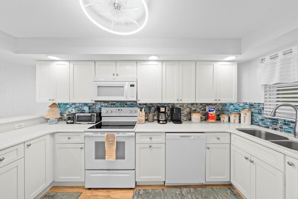 A modern kitchen with white cabinets, a microwave, stove, and dishwasher. - #803 Shores Club Oceanfront Traffic Free Beach 2/2 (Daytona Beach Shores)