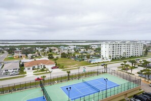 Ein Tennisplatz mit Blick auf eine Wohngegend und ein großes Gebäude im Hintergrund.