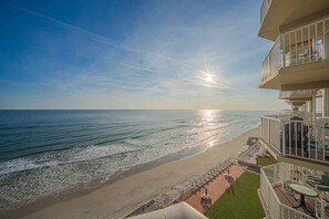 Ein Strandhotel mit Balkon mit Blick auf den Ozean, einer Terrasse mit Sitzgelegenheiten und freiem Blick auf den Sonnenuntergang.