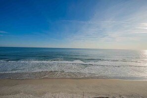 Una playa con cielos despejados y olas suaves.