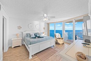 Ein Schlafzimmer mit Bett, Nachttisch und Blick auf den Ozean.
