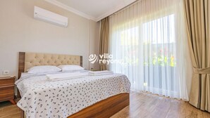 Een slaapkamer met een groot bed, een nachtkastje, een wandairconditioner en dunne gordijnen.