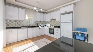 Een moderne keuken met witte kasten, een zwart aanrecht en een blauwe stoel.