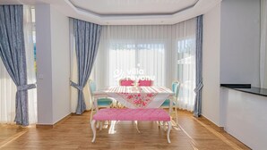 Un coin repas avec une table dressée pour deux personnes, un banc et des rideaux.