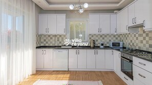 Una cocina moderna con armarios blancos, microondas, cafetera y estufa.