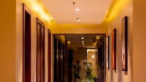 A hallway with a polished floor, framed artwork on the walls, and a glass door leading to another room.