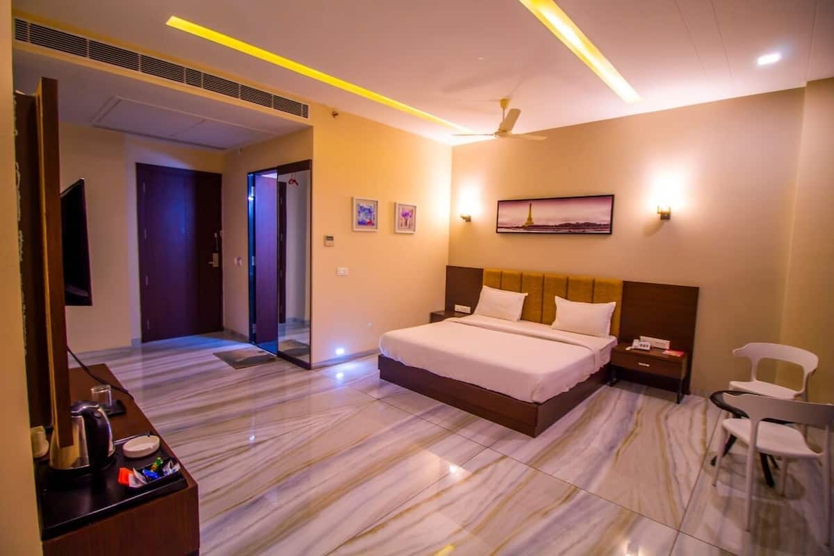 A hotel room with a large bed, a desk with a chair, a flat-screen TV, and a painting on the wall.