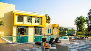 A modern building with a pool area featuring lounge chairs and a checkered floor.