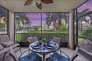 A balcony with a table set for two, featuring a view of palm trees and buildings.