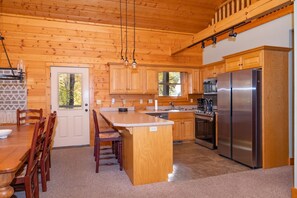 A wooden cabin-style kitchen with a central island, built-in cabinets, and stainless steel appliances. - Mountain Dream - New Hot Tub! in Gated Smoky Mountain Retreat Community (Maggie Valley)