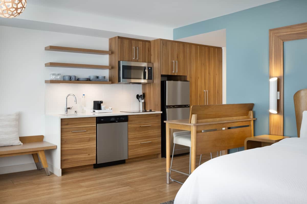 A modern kitchen with wooden cabinets, a stainless steel refrigerator, a microwave, and a dishwasher.