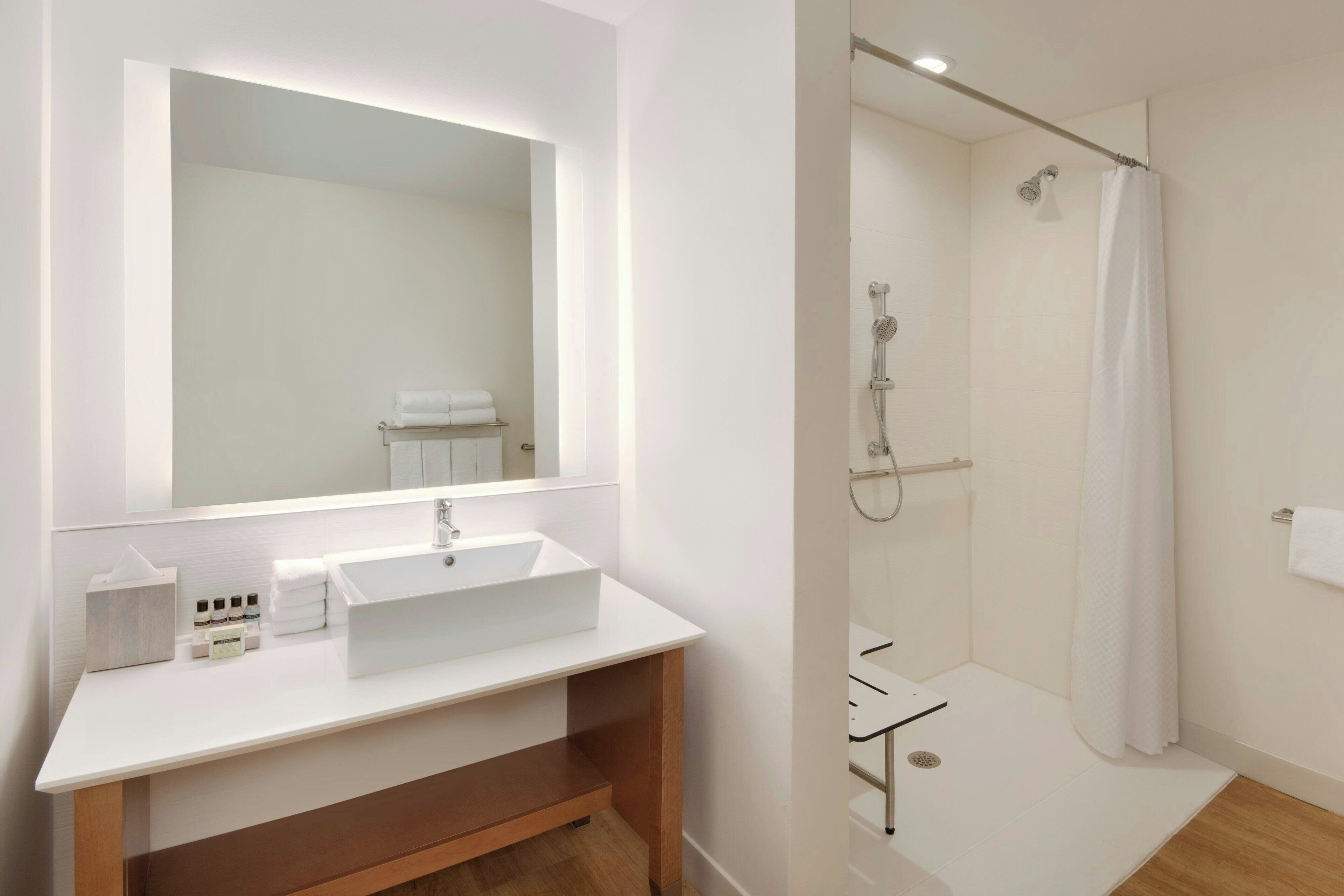 A modern bathroom with a white sink, mirror, and shower.