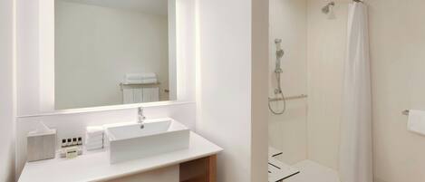 A modern bathroom with a white sink, mirror, and shower.