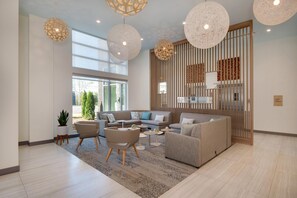 A modern living room with a sectional sofa, armchairs, and a coffee table. There are hanging spherical light fixtures and a large window providing natural light.