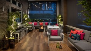 A modern outdoor seating area with brick walls, wooden flooring, and a large screen displaying a presentation. - Element by Marriott Atlanta Buckhead (Atlanta)