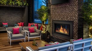 A cozy outdoor seating area with a fireplace, brick walls, and a view of the cityscape. - Element by Marriott Atlanta Buckhead (Atlanta)