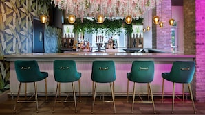 A bar area with a counter, green bar stools, hanging floral decorations, and pendant lights. - Element by Marriott Atlanta Buckhead (Atlanta)