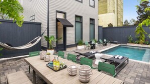 A modern outdoor patio with a pool, dining area, and seating.