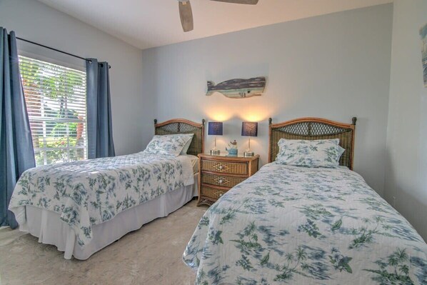 A bedroom with two beds, a nightstand with a lamp, and a wall-mounted artwork.