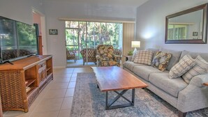 A living room with a sofa, a wooden coffee table, a television, and a rattan cabinet.