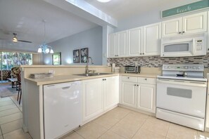A kitchen with white cabinets, a microwave, a toaster, and a dishwasher.
