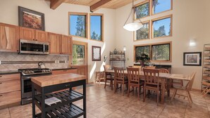 A spacious kitchen with wooden cabinets, a stainless steel stove, and a dining area with a wooden table and chairs. - Beautiful home in Fraser with great breathtaking views and private hot tub (Fraser)