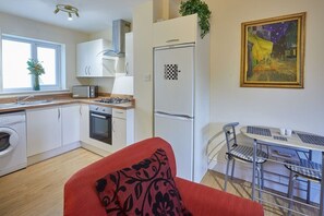 A compact kitchen with a microwave, stove, sink, and a refrigerator. There is a dining area with a table and chairs.