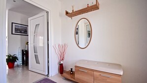 A modern bathroom with a wooden vanity, a mirror, and a vase with branches. - Relaxing rural apartment with playground and grill (Nedescina)