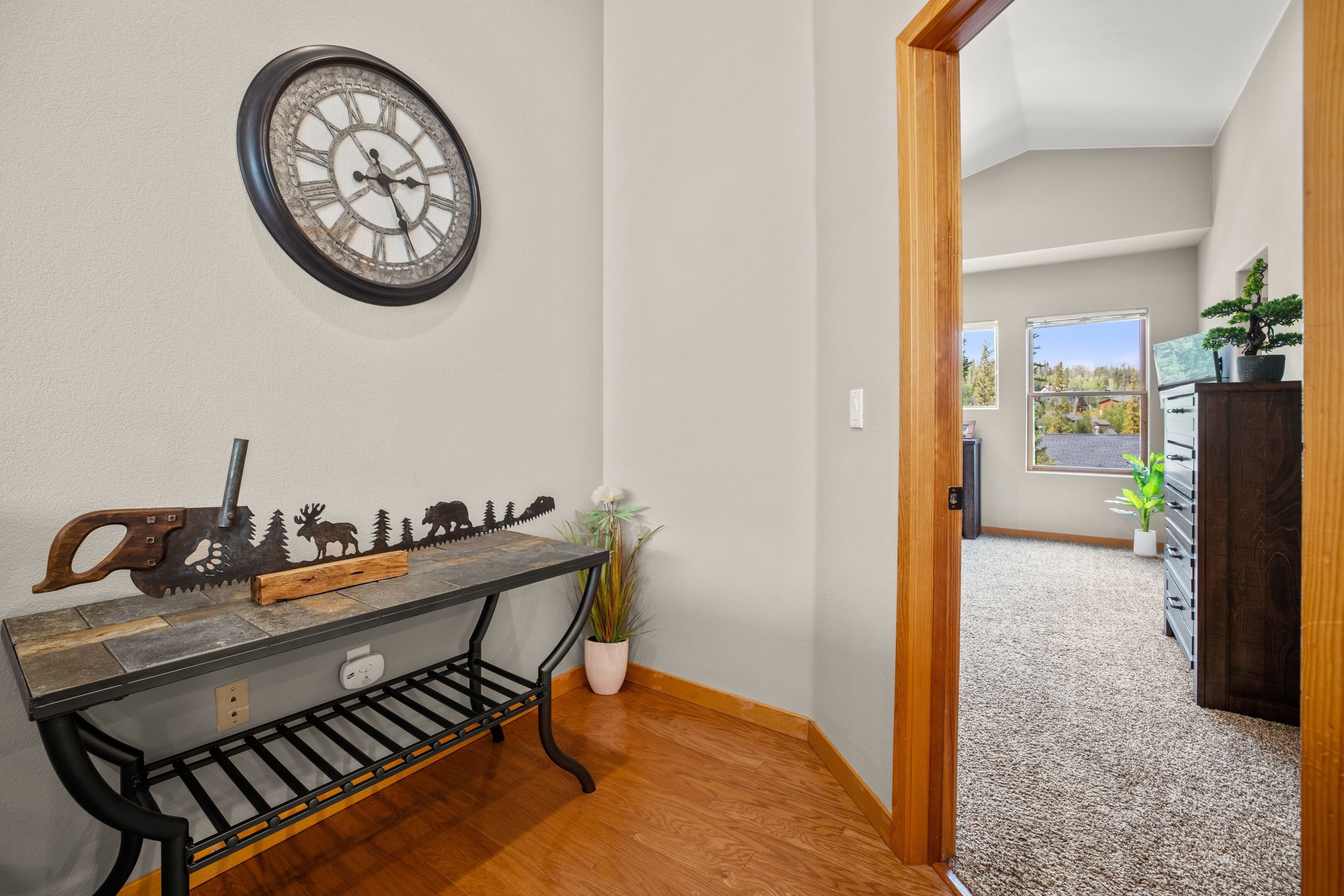 A hallway with a wooden bench, a decorative clock, and a potted plant.