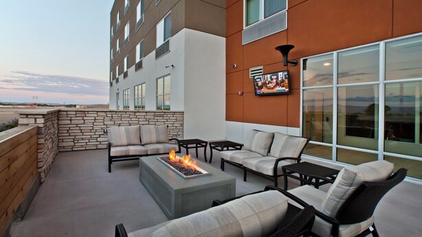 An outdoor patio with stone walls, a fire feature, and seating arrangements. - Holiday Inn Express & Suites Green River by IHG (Green River)