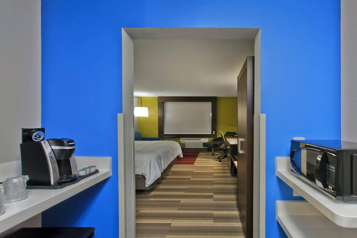 Une chambre d’hôtel équipée d’un lit, d’un bureau, d’un four à micro-ondes et d’une machine à café.