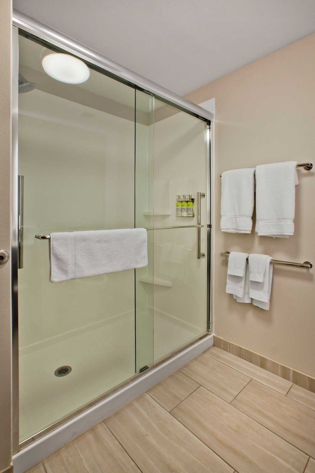 A glass-enclosed shower with a white towel hanging on the door.