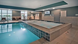 A swimming pool with a tiled deck, a lounge area with chairs, and a television screen on the wall. - Holiday Inn Express & Suites Green River by IHG (Green River)
