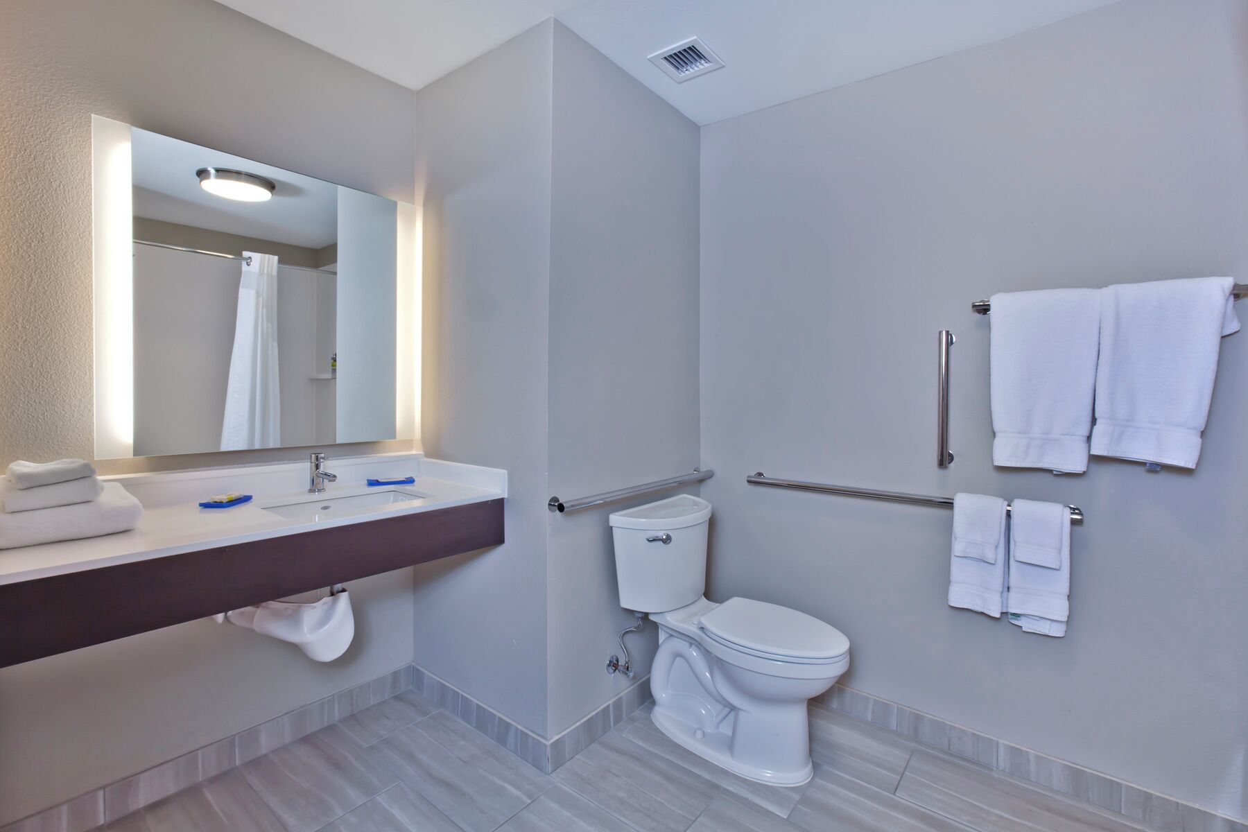 A modern bathroom with a sink, mirror, toilet, and shower.