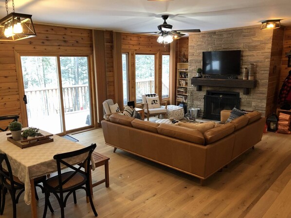 A cozy living room with a sofa, a fireplace, a television, and a dining area with a table and chairs.