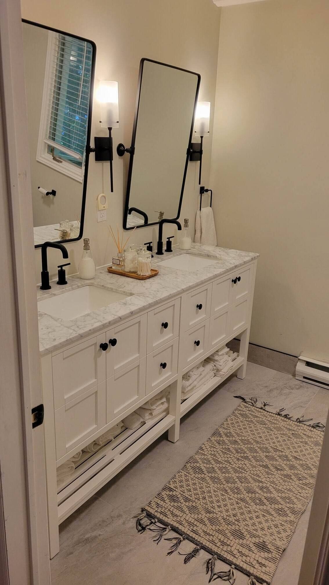A bathroom with a white vanity, two mirrors, a sink, and a towel rack.