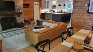 Un salon chaleureux avec un canapé en cuir, une cheminée et un coin repas comprenant une table et des chaises.