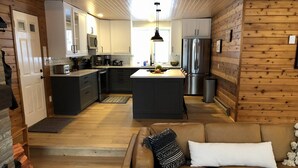 Une cuisine compacte dotée d’appareils électroménagers modernes, d’un îlot central et d’un coin salon accueillant avec un canapé en cuir.
