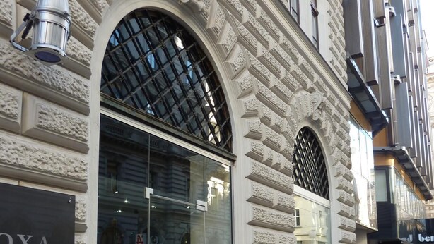 A building facade with ornate architectural details, including a large arched window and decorative stonework.