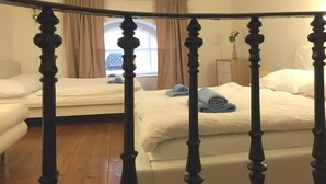 A bedroom with two beds, a wooden headboard, a window with curtains, and a wooden floor.