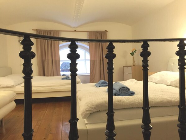 A bedroom with two beds, a wooden headboard, a window with curtains, and a wooden floor.