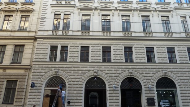 Ein mehrgeschossiges Gebäude mit klassischer Architektur, das durch rundbogige Portale und eine symmetrische Fassade gekennzeichnet ist.