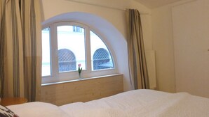 Ein Hotelzimmer mit einem großen Bogenfenster, einem hölzernen Kopfteil und einem Bett mit weißer Bettdecke.