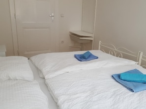 Two single beds with white bedding and a neatly made towel.