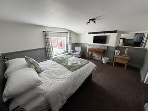 A hotel room with a bed, a desk, a chair, a TV, and a window with curtains. - George & Dragon (Chester)