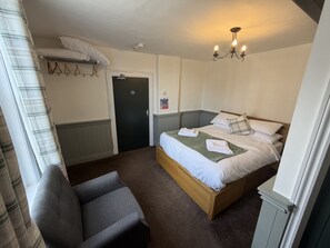 A bedroom with a bed, a chair, a door, and a hanging laundry rack. - George & Dragon (Chester)